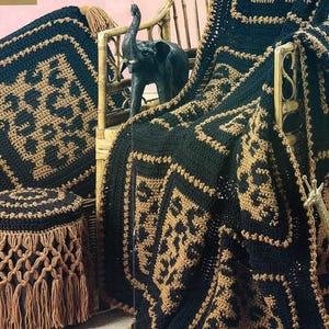 Puede incluir: Un conjunto de artículos de ganchillo hechos a mano en negro y marrón. El conjunto incluye una manta, un cojín cuadrado y un taburete redondo con una falda de macramé. La manta y el cojín presentan un patrón geométrico, el taburete tiene un borde con flecos.