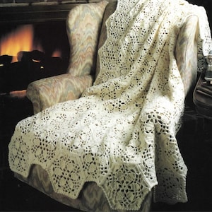 May include: A white crocheted throw blanket with a delicate floral pattern, draped over a chair in front of a fireplace.