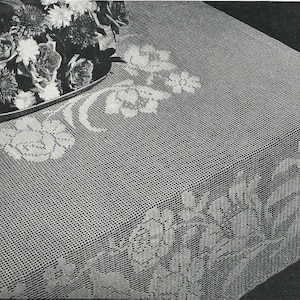 Può includere: Una tovaglia all'uncinetto bianca con un motivo floreale. La tovaglia presenta un motivo ripetitivo di rose e foglie.