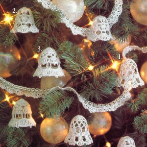 May include: A close-up of a Christmas tree decorated with white crocheted bells and a white crocheted garland. The bells are numbered 1, 2, and 3.