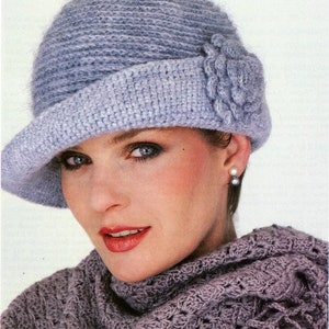 May include: A light blue crocheted hat with a flower detail. The hat has a wide brim and is worn by a person with a scarf.