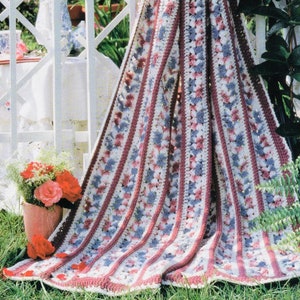 May include: A crocheted blanket featuring stripes of pink, blue and white. The blanket is crafted using a simple stitch pattern and has a soft, textured feel.