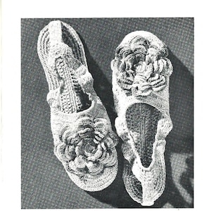 May include: A pair of crocheted slippers with a floral design. The slippers are white and have a delicate, feminine look.
