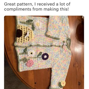 Puede incluir: Un c&aacute;rdigan de beb&eacute; tejido a crochet con un patr&oacute;n de cuadros pastel y aplicaciones florales. El c&aacute;rdigan tiene un dise&ntilde;o de colmena en la parte delantera y un gorro a juego.