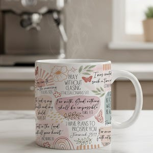May include: A white ceramic mug featuring a wrap-around design with various inspirational Bible verses in black script and serif fonts, interspersed with illustrations of butterflies, flowers, leaves, and sunbursts in muted pink, orange, and green tones.