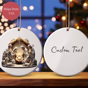 May include: White ceramic Christmas ornament with a Nativity scene on one side and the words "Custom Text" on the other. The Nativity scene depicts Mary, Joseph, baby Jesus, and other figures. The ornament has a gold string for hanging.