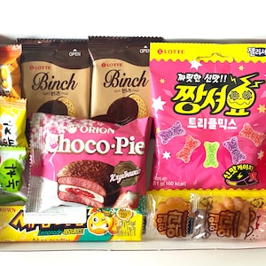 May include: A selection of packaged snacks in a red box. The contents include chocolate biscuits, pink Choco-Pie pastries, and a bright pink bag of gummy sweets. Other individually wrapped snacks are also visible.