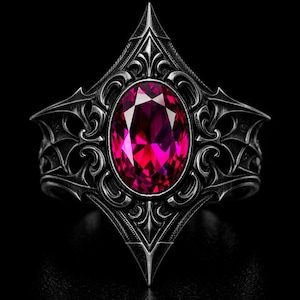 May include: A gothic-style ring with a large, oval-cut, magenta gemstone set in a detailed, dark silver-toned metal band. The ring features ornate filigree and pointed accents, creating a bold and striking design. The ring is set against a black background.