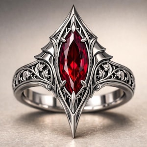 May include: A silver ring featuring a large, marquise-cut, deep red gemstone. The ring has an ornate, gothic-inspired design with intricate detailing around the gemstone and along the band. The ring's setting is pointed at the top and bottom.
