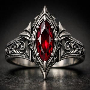 Könnte beinhalten: Ein silberner Ring mit einem großen, ovalen, tiefroten Edelstein in der Mitte. Der Ring hat ein verziertes, gotisches Design mit spitzen Akzenten und detaillierten Schnörkeln entlang des Bandes. Der Edelstein ist facettiert und der Ring hat ein dunkles, antikes Finish.