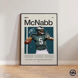 May include: A framed poster featuring Donovan McNabb in an Eagles uniform. The poster has a beige background with the name "McNabb" in large black letters. McNabb is shown throwing a football, with his signature and the number 5 visible.