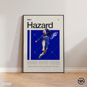 Puede incluir: Un póster enmarcado con el nombre "Hazard" y una foto de un futbolista con uniforme azul celebrando. El póster tiene un fondo azul y una firma. Se muestra en una pared clara, con suelo de madera.