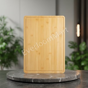 May include: A rectangular bamboo chopping board in a light brown hue. It features a recessed groove around the edges and the text "EverloomMart". The board is displayed on a round, grey marble surface.