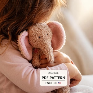 Op de afbeelding: Een pluche olifant met krullende beige vacht, grote roze gevoerde oren en een kleine roze knoop op de borst. Een wit rechthoekig label toont de tekst: DIGITAL PDF PATTERN ENGLISH, vergezeld van een icoon van de Amerikaanse vlag.