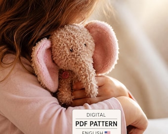 May include: A plush elephant toy with curly beige fur, large pink-lined ears, and a small pink button on its chest. A white rectangular label is overlaid on the image with the text: DIGITAL PDF PATTERN ENGLISH, accompanied by a US flag icon.