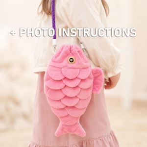 May include: A plush pink fish-shaped bag with a textured scale pattern, a single circular eye detail, and a purple braided strap. The bag features the text + PHOTO INSTRUCTIONS overlaid in white, indicating that visual guidance is included.