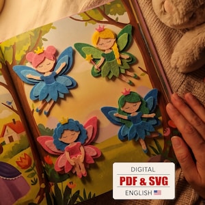 May include: Four layered felt fairy cutouts featuring pink, yellow, blue, and green hair and wings, each wearing a small crown. The fairies are displayed on an illustrated book page. A white label in the corner reads DIGITAL PDF & SVG ENGLISH.