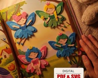 May include: Four layered felt fairy cutouts featuring pink, yellow, blue, and green hair and wings, each wearing a small crown. The fairies are displayed on an illustrated book page. A white label in the corner reads DIGITAL PDF & SVG ENGLISH.