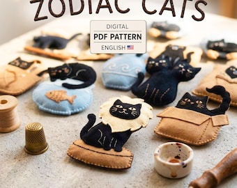 May include: A digital PDF pattern titled ZODIAC CATS featuring various felt cat shapes, including a lion-maned cat, a cat in a box, and a cat with a fish. The image includes sewing tools like a thimble, a wooden spool, and a needle tool.