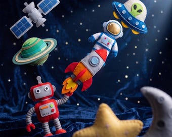 Könnte beinhalten: Eine Sammlung von Weltraum-Ornamenten aus Filz, bestehend aus einem grauen Satelliten, einem grün-blauen Planeten, einem roten Roboter, einer bunten Rakete, einem Astronauten im weißen Anzug, einem blauen UFO mit Alien, einem gelben Stern und einem grauen Mond.