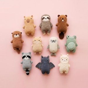 May include: A collection of ten small plush animal toys featuring a capybara, sloth, beaver, otter, hamster, seal, frog, raccoon, bat, and llama. Each stuffed animal is crafted from textured fabric in various colors including brown, gray, and white.