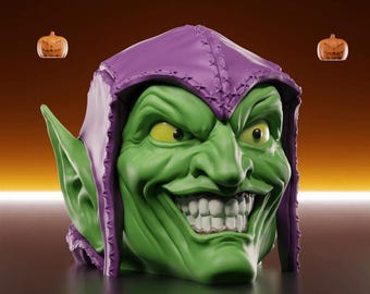 May include: A green, grinning sculpted head with pointed ears and yellow eyes, wearing a purple hood. Two small jack-o'-lanterns float in the background. The head has a sinister expression with sharp teeth, perfect for Halloween or comic book fans.