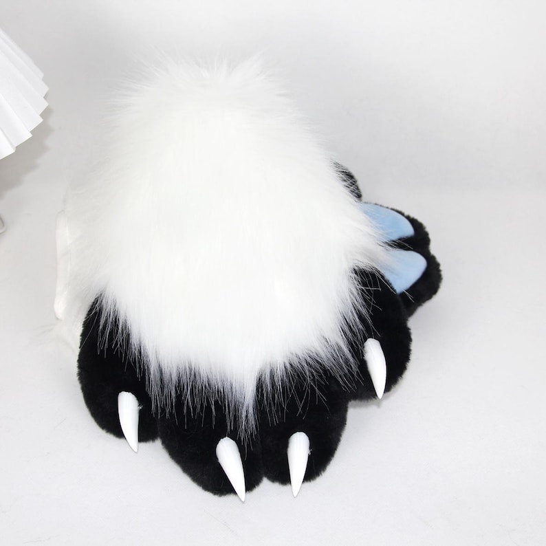 May include: A plush paw with black pads, white claws, and a large tuft of white fur. The paw has light blue accents and is designed to resemble an animal's paw. The item is likely a costume accessory or a novelty item.