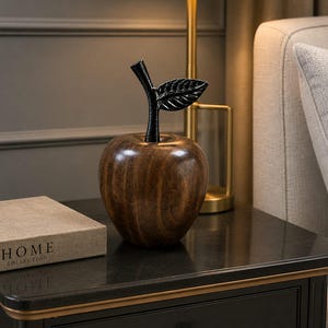 Peut inclure: Une sculpture décorative en forme de pomme avec un corps en bois brun foncé au grain poli et une tige en métal noir contrastant surmontée d'une feuille texturée. L'objet présente une forme arrondie et lisse avec des motifs de bois naturels.