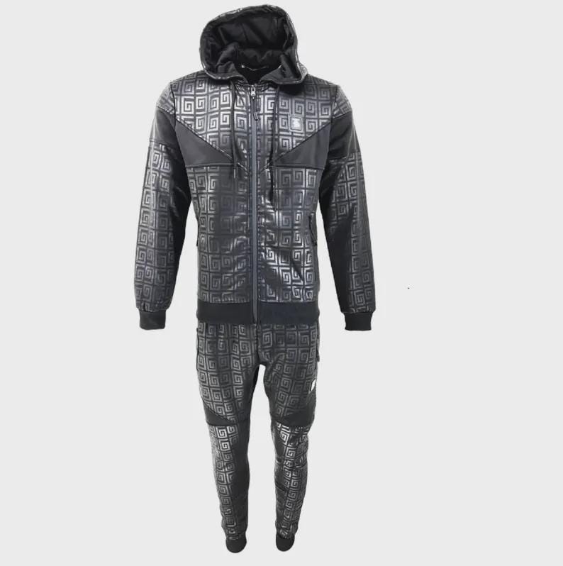 May include: Black tracksuit set with a geometric pattern. The set includes a hooded zip-up jacket and matching trousers. The jacket features a black hood and black accents on the shoulders. The trousers have a pocket on the side.