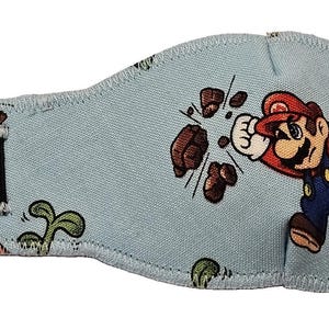Puede incluir: Parche ocular azul claro con una imagen bordada de Mario de Super Mario Bros. Mario golpea bloques marrones. El parche tiene una correa elástica negra. El diseño es del popular videojuego.