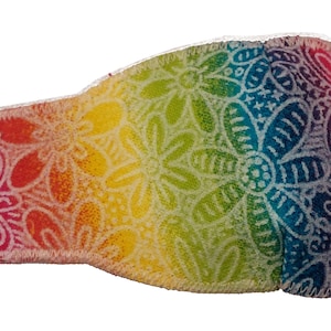 May include: A rainbow eye patch with a white floral pattern. The patch has an elastic strap for a secure fit.