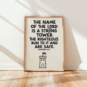 May include: A rectangular wall art print in a light wood frame featuring black text that reads: THE NAME OF THE LORD IS A STRONG TOWER. THE RIGHTEOUS RUN TO IT AND ARE SAFE. PROVERBS 18:10. Below the text is a simple line drawing of a grey stone tower with a red flag.