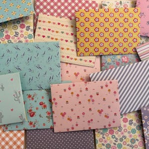 Peut inclure: Un assortiment d'enveloppes en papier à motifs variés. Les motifs comprennent des fleurs, des cœurs, des rayures, des pois et des formes géométriques. Les couleurs varient du rose, jaune, bleu et blanc, créant un ensemble visuellement attrayant.