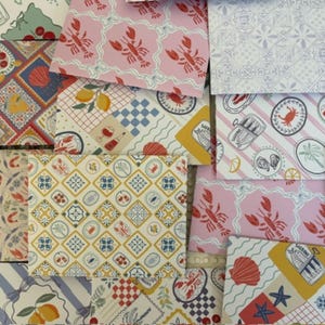 Op de afbeelding: Assortiment van papieren vellen met patronen met nautische en kustthema's. Ontwerpen omvatten kreeften, citroenen, schelpen en geometrische patronen in verschillende kleuren zoals roze, blauw, geel en wit. Ideaal voor knutselen en scrapbooking.