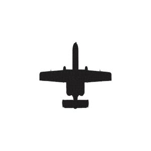 May include: A black embroidered patch featuring the silhouette of an A-10 Thunderbolt II aircraft. The design shows the top-down view of the plane with its straight wings, twin engines mounted on the rear fuselage, and a distinct tail section.
