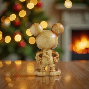 May include: A wooden Mickey Mouse figurine with large round ears, shorts, and a detailed carved design. The figurine is standing on a wooden surface, with a blurred background of Christmas lights and a fireplace.