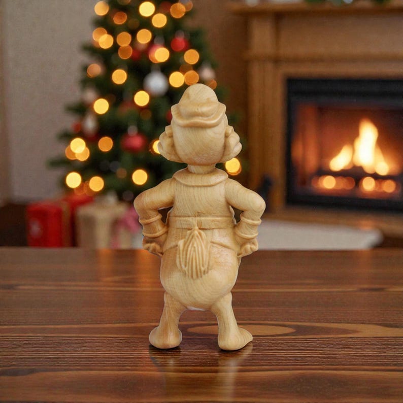 May include: A wooden figurine of a character with a hat and a long tail, standing with hands on hips. The figurine is light brown and stands on a wooden surface. A Christmas tree and fireplace are in the background.