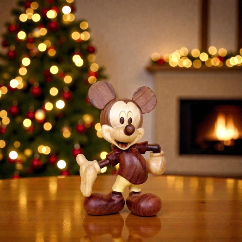 May include: A wooden Mickey Mouse figurine with a brown body, ears, and shoes, and a tan face and gloves. The figurine is posed on a wooden surface, with a Christmas tree and fireplace in the background.