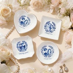 May include: Four white ceramic trinket dishes in heart, square, scalloped square, and round shapes. Each dish features a blue and white portrait design with a gold rim. The dishes are personalized with names.