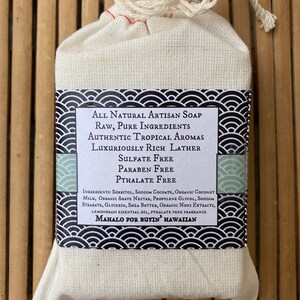 May include: A white muslin bag with a drawstring closure containing a bar of natural artisan soap. The soap label features black and white waves and text that reads "All Natural Artisan Soap, Raw, Pure Ingredients, Authentic Tropical Aromas, Luxuriously Rich Lather, Sulfate Free, Paraben Free, Phthalate Free, Ingredients: Sorbitol, Sodium Cocoate, Organic Coconut Milk, Organic Agave Nectar, Propylene Glycol, Sodium Stearate, Glycerin, Shea Butter, Organic Noni Extracts, Lemongrass Essential Oil, Phthalate Free Fragrance, Mahalo for Buyin' Hawaiian."