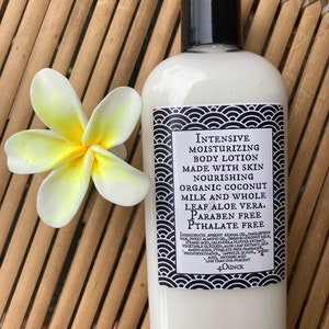 May include: A white bottle of moisturizing body lotion with a black cap and a decorative label. The label features text and a black and white wave pattern. A white and yellow flower rests beside the bottle. The bottle contains 4 ounces of lotion.