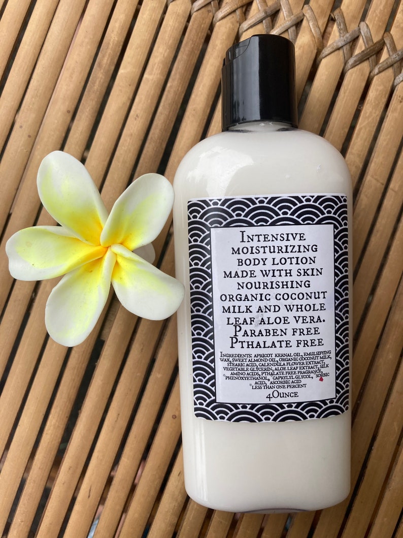 May include: A white bottle of moisturizing body lotion with a black cap and a decorative label. The label features text and a black and white wave pattern. A white and yellow flower rests beside the bottle. The bottle contains 4 ounces of lotion.