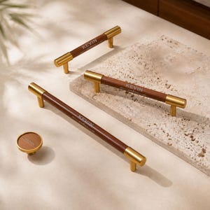 May include: Three cabinet pulls and one round cabinet knob featuring a dark brown cylindrical centre with gold-toned metal ends and mounts. Each piece is engraved with the name KEVIN in a clean, sans-serif font on the brown surface.