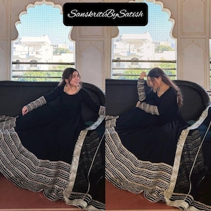May include: A black dress with gold and white trim and the text "SanskritiBySatish" in a black box. The dress has long sleeves with gold and white detailing on the cuffs. The hemline and neckline are also trimmed with gold and white.