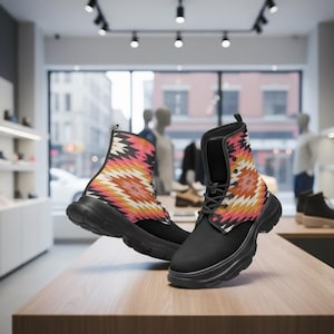 Può includere: Un paio di stivali da combattimento neri con un motivo geometrico colorato sulla tomaia. Gli stivali, con una suola spessa, sono esposti su un tavolo di legno in un negozio di scarpe. Il motivo include sfumature di rosa, arancione e giallo.