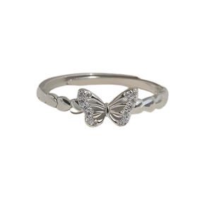 May include: A silver-colored ring featuring a butterfly design. The butterfly has a detailed wing pattern and is embellished with small, clear gemstones. The band has a textured design. The ring is set against a white background.