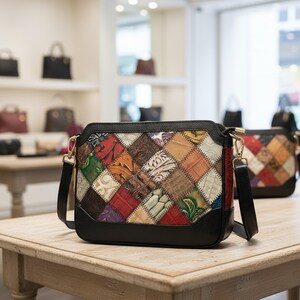 Könnte beinhalten: Eine mehrfarbige Patchwork-Umhängetasche mit schwarzem Boden und Besatz. Die Tasche hat eine Vielzahl von Lederquadraten in Rot-, Grün-, Orange- und Brauntönen. Die Tasche hat einen langen schwarzen Riemen und goldfarbene Beschläge. Weitere Taschen sind im Hintergrund zu sehen.