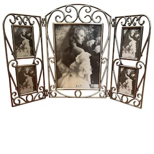 May include: A bronze-colored, three-panel photo frame with a decorative, scrolled design. The center frame holds a 5x7 inch photo, while the side panels each hold two 2x3 inch photos. The frame is open and displays black and white photos.
