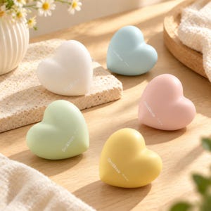 May include: Five smooth, heart-shaped objects in pastel colours including white, light blue, pale pink, mint green, and soft yellow. Each heart features the printed text Chris&Nicole on the front surface, arranged in a cluster on a wooden surface.