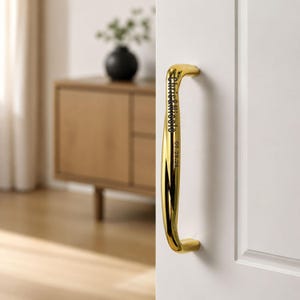 May include: A polished gold-tone metal door handle mounted on a white door. The handle features a curved, twisted design with the engraved text "Chris & Nicole" and the date "05.28.24" clearly visible along the front surface of the metal.
